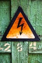 Old rusty warning high voltage sign on cracked wooden surface Royalty Free Stock Photo