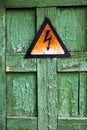 Old rusty warning high voltage sign on cracked wooden surface Royalty Free Stock Photo