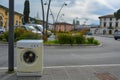 An old rusty washing machine on the sidewalk in italian town. Illegal waste dump in a parking lot
