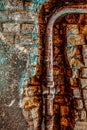 Old rusty water pipe in a brick wall.  Old rusty pipe with valves on painted brick wall with rectangle recess. Urban build texture Royalty Free Stock Photo