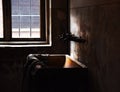 Old rusty water tap and a bathtub next to a window in an abandoned weathered building in Auschwitz