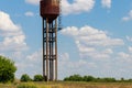 Old rusty water tower in green field Royalty Free Stock Photo