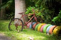 Old rusty weathered bicycle leaning on row of decorative colorful tires on tropical island Royalty Free Stock Photo