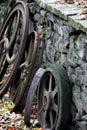 Old rusty wheels set against stone wall