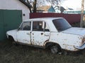 old rusty white car without wheels outdoor