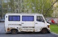 An old rusty white minibus is parked in the courtyard of a residential building