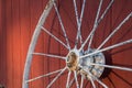 Old rusty white wagon wheel leaning against a red barn Royalty Free Stock Photo