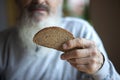 Old sad man with a long gray beard sitting by the table and eating bread Royalty Free Stock Photo