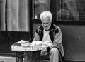 An old sad man sitting on a stone brick near the Bucharest city center