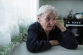 An old sad woman sitting in the kitchen of her apartment Royalty Free Stock Photo