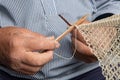 Old sailer mending a fishing net, the tradional way by hand