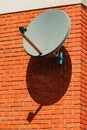 Old satellite dish mounted on house brick wall Royalty Free Stock Photo
