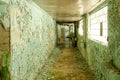 Old, scary hallway with green cracked paint, radiators and windows. Forgotten, abandoned ghost town Skrunda, Latvia. Former Soviet