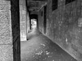 Old and scary looking exterior hallway corridor next to an old building with dark and abandoned feeling to it in black and white