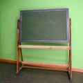 Old school blackboard or chalkboard to use chalk to write on against a green wall, copy space Royalty Free Stock Photo