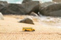 Old school bus toy on the sand of the beach. Blurred sea and stones background Royalty Free Stock Photo