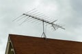 Old school television satelite on top of house or home for radio on red tiled rooftop with storm clouds in distance Royalty Free Stock Photo