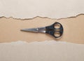 Old scissors lie in the center of torn sheets of cardboard paper.Dark paper with torn edges isolated on a dark background of color Royalty Free Stock Photo