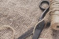 Old scissors and skein jute twine on a burlap, selective focus, rustic style. Royalty Free Stock Photo