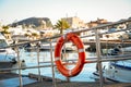 Old scratched red lifebuoy hanging on metal railing, on the background of marina. Sea shore, sunny day, outdoor Royalty Free Stock Photo