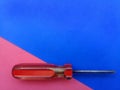 Old screwdriver with red handle and colorful background