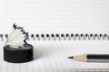 An old, second-hand, sharpener with a shavings and a simple pencil lie on the notebook in a box. Selective focus. Close-up.