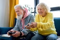 Old senior couple holding a console pad, entertaining video games playing at home Royalty Free Stock Photo