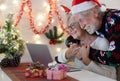 Old senior couple hugging happy in video call with family in Christmas time. Beautiful elderly caucasian family celebrating new Royalty Free Stock Photo