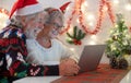 Old senior couple laughing happy in video call with family in Christmas time. Beautiful elderly caucasian people celebrating new Royalty Free Stock Photo