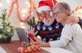 Old senior couple smiling happy in video call with family in Christmas time. Beautiful elderly caucasian family celebrating new Royalty Free Stock Photo