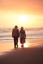 old senior couple walking by sea beach at sunset, older romantic man and woman walk by ocean shore at summer sunrise Royalty Free Stock Photo