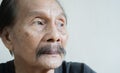 Old senior man closeup serious expression portrait over white wall background