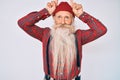 Old senior man with grey hair and long beard wearing hipster look with wool cap doing funny gesture with finger over head as bull Royalty Free Stock Photo