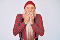 Old senior man with grey hair and long beard wearing hipster look with wool cap laughing and embarrassed giggle covering mouth Royalty Free Stock Photo