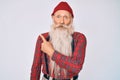 Old senior man with grey hair and long beard wearing hipster look with wool cap surprised pointing with finger to the side, open Royalty Free Stock Photo