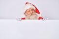 Old senior man with grey hair and long beard wearing santa claus costume holding banner winking looking at the camera with sexy Royalty Free Stock Photo