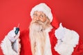 Old senior man with grey hair and long beard wearing santa claus costume holding car keys smiling happy and positive, thumb up Royalty Free Stock Photo