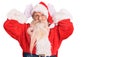 Old senior man with grey hair and long beard wearing traditional santa claus costume doing bunny ears gesture with hands palms Royalty Free Stock Photo