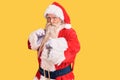 Old senior man with grey hair and long beard wearing traditional santa claus costume ready to fight with fist defense gesture, Royalty Free Stock Photo