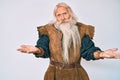 Old senior man with grey hair and long beard wearing viking traditional costume clueless and confused with open arms, no idea Royalty Free Stock Photo