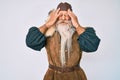 Old senior man with grey hair and long beard wearing viking traditional costume with hand on head, headache because stress Royalty Free Stock Photo