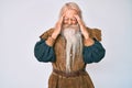 Old senior man with grey hair and long beard wearing viking traditional costume with hand on head, headache because stress Royalty Free Stock Photo