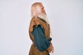 Old senior man with grey hair and long beard wearing viking traditional costume looking to side, relax profile pose with natural Royalty Free Stock Photo