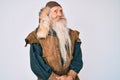 Old senior man with grey hair and long beard wearing viking traditional costume looking to side, relax profile pose with natural Royalty Free Stock Photo