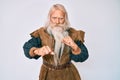 Old senior man with grey hair and long beard wearing viking traditional costume ready to fight with fist defense gesture, angry Royalty Free Stock Photo