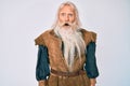 Old senior man with grey hair and long beard wearing viking traditional costume in shock face, looking skeptical and sarcastic, Royalty Free Stock Photo