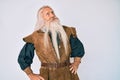 Old senior man with grey hair and long beard wearing viking traditional costume smiling looking to the side and staring away Royalty Free Stock Photo