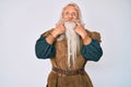 Old senior man with grey hair and long beard wearing viking traditional costume smiling with open mouth, fingers pointing and Royalty Free Stock Photo