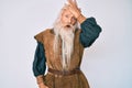 Old senior man with grey hair and long beard wearing viking traditional costume surprised with hand on head for mistake, remember Royalty Free Stock Photo