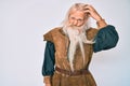 Old senior man with grey hair and long beard wearing viking traditional costume worried and stressed about a problem with hand on